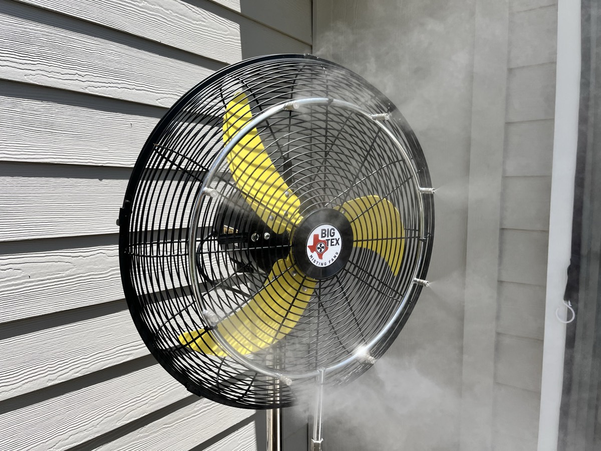 Big Tex pedestal misting fan throwing a fine, dry mist across the patio