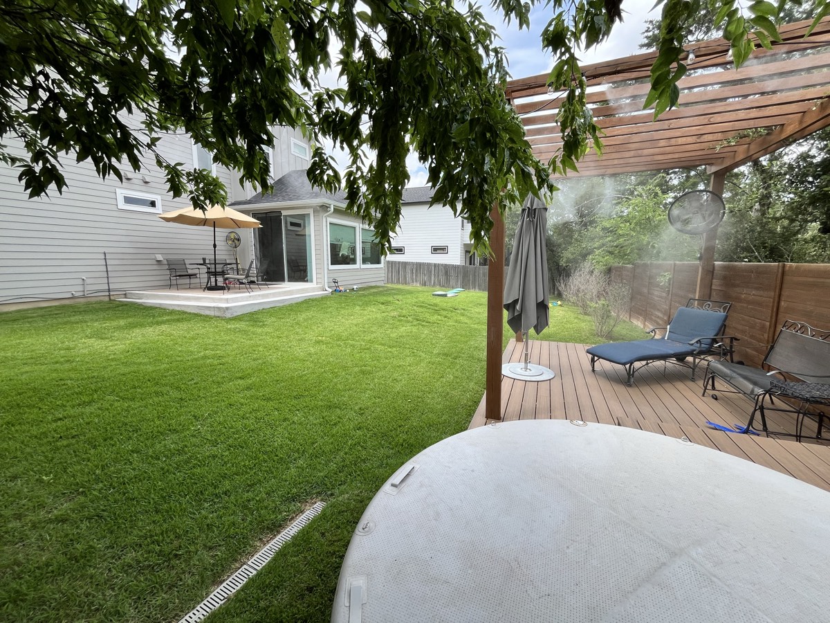Pergola misting system cooling a backyard deck lounge and hot tub