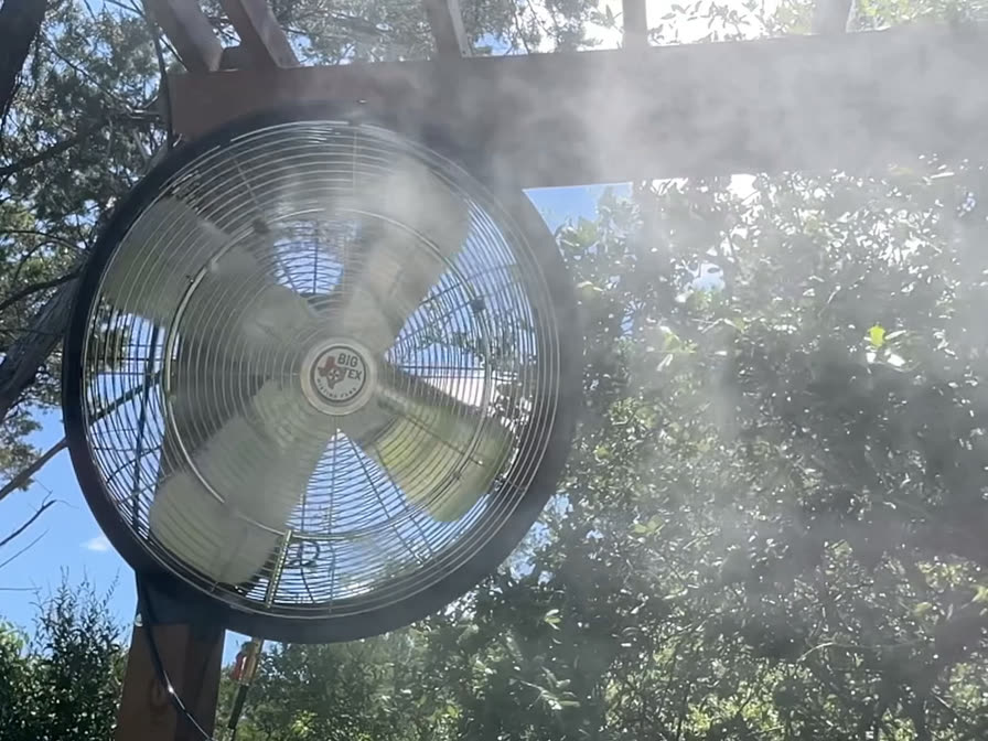 Big Tex misting fan cooling a shaded pergola with a fine mist plume